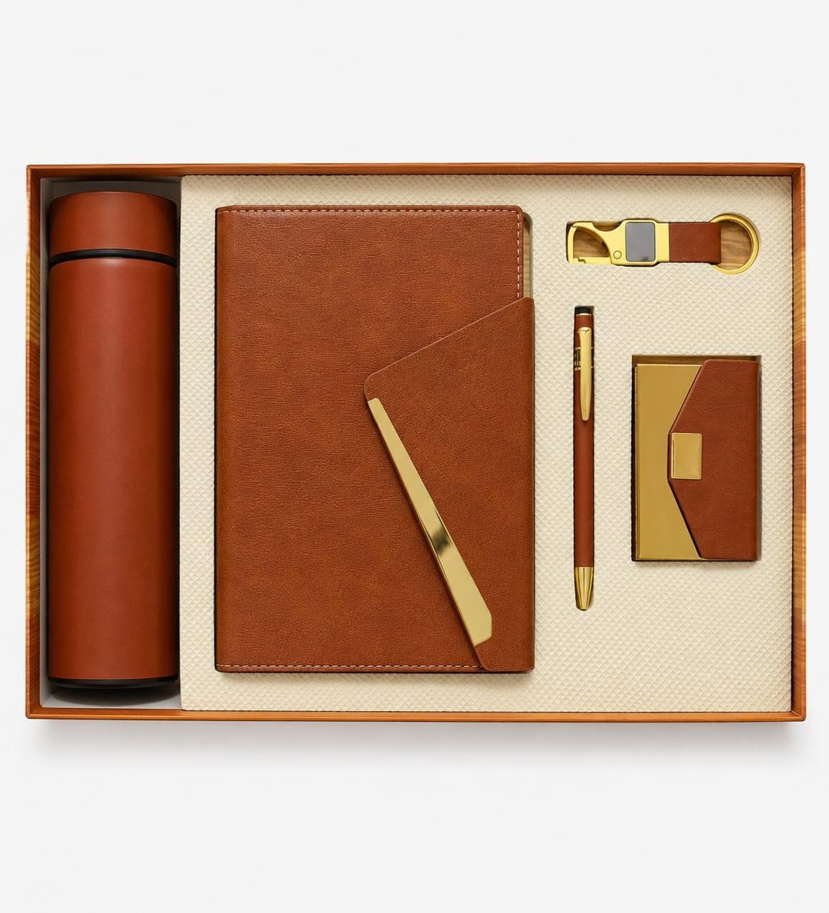 Cognac leather gift set laid flat in a tray — insulated flask, A5 notebook with brass flap, pen, keychain and card holder